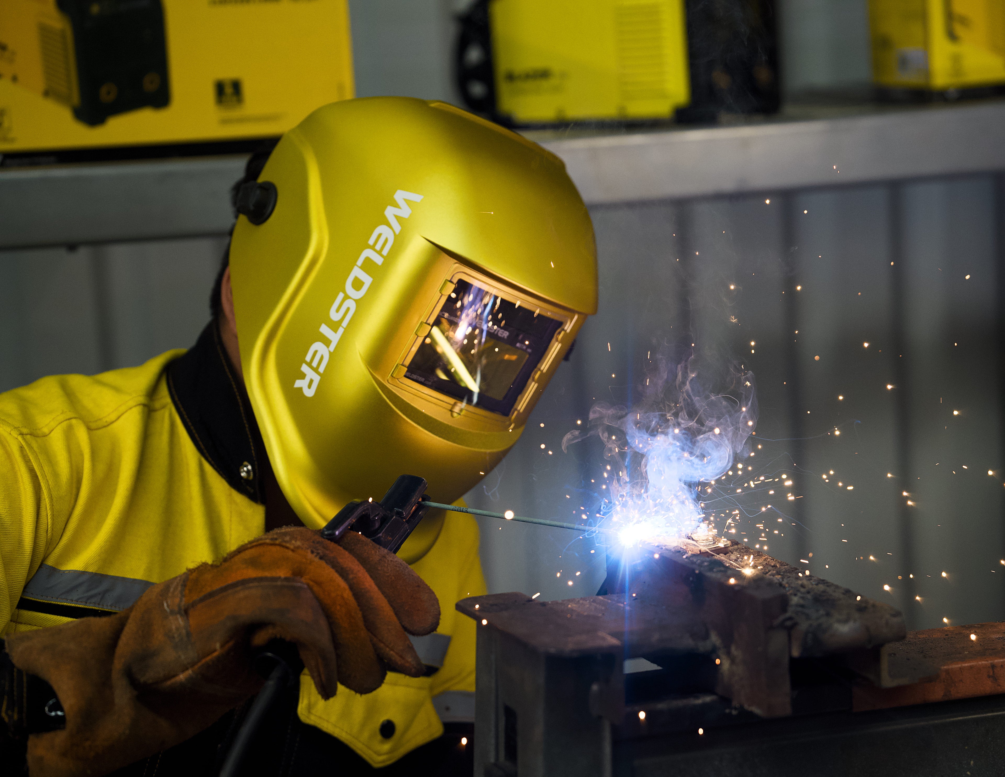 Soldador usando la careta WELDSTER Goldarized dorada mientras suelda con arco eléctrico